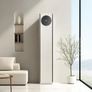 카밍 베이지 컬러의 LG 휘센 AI 오브제컬렉션 타워I 에어컨이 밝은 미니멀 인테리어 공간의 중앙에 세워져 있습니다. 에어컨 본체 상단에 원형 블랙 디지털 디스플레이 화면에서 온도 정보를 숫자로 표시하고 있습니다. 에어컨은 연한 베이지색 벽 앞에 놓여 있으며, 벽면에는 벽 매립 선반이 있고 선반에는 도기로 된 꽃병과 책이 놓여 있습니다. 
