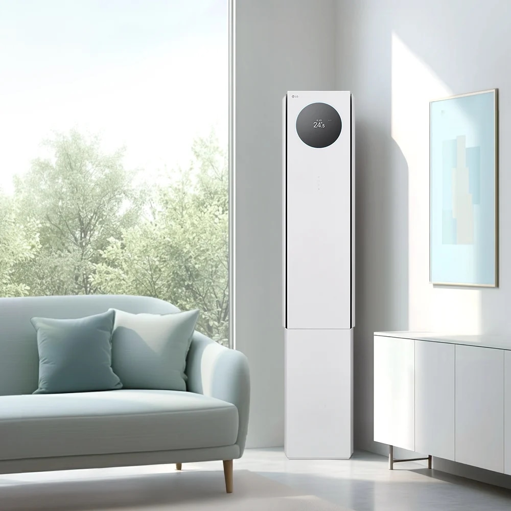 에센스 화이트 컬러의 LG 휘센 AI 오브제컬렉션 뷰I 프로 에어컨이 밝은 미니멀 인테리어 공간의 우측에 세워져 있습니다. 에어컨 본체 상단에 원형 블랙 디지털 디스플레이 화면에서 온도 정보를 숫자로 표시하고 있습니다. 에어컨은 연한 회색 벽 앞에 놓여 있으며, 벽면에는 금색 테두리에 하늘색 추상화 액자가 걸려 있습니다.