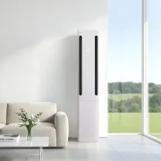 에센스 화이트 컬러의 LG 휘센 AI 오브제컬렉션 쿨 에어컨이 모던한 인테리어 공간의 중간에 배치되어 있습니다. 스탠드 에어컨 옆으로는 통창이 있고 밖으로는 초록색 들판과 나무들이 생기있는 모습을 보여줍니다. 에어컨 본체 상단의 디지털 디스플레이 화면에서 온도 정보를 숫자로 표시하고 있습니다. 에어컨은 연한 화이트 컬러 벽 앞에 놓여 있으며, 스탠드 에어컨