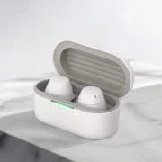LG XBOOM 버즈 화이트 모델의 무선 이어폰 케이스가 열려 있는 모습입니다. 둥근 형태의 케이스는 흰색이며, 케이스 안에는 두 개의 흰색 이어폰이 자리하고 있습니다. 케이스 앞쪽에는 녹색으로 켜진 작은 LED 불빛이 보입니다. 밝은 색의 배경 위에 케이스가 정중앙에 배치되어 있습니다.