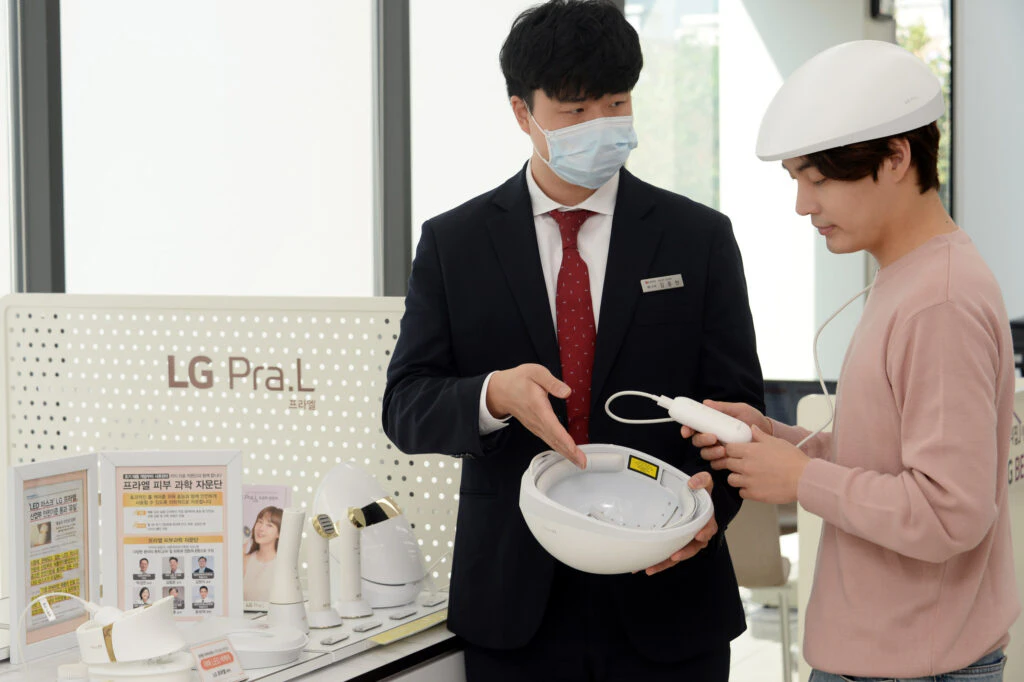 LG 프라엘 메디헤어 제품을 착용한 모델과 설명하는 임직원