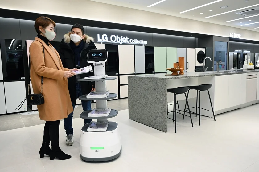 LG베스트샵 서초본점을 방문한 고객들이 LG 클로이 서브봇이 가져다주는 안내책자를 살펴보고 있다. 