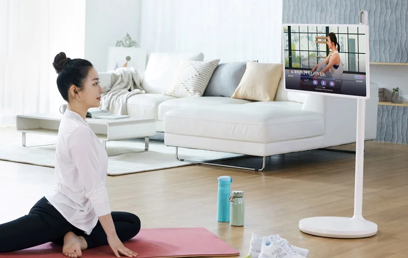 모델이 LG 피트니스 앱으로 피트니스  영상을 보며 스트레칭을 하고 있다.