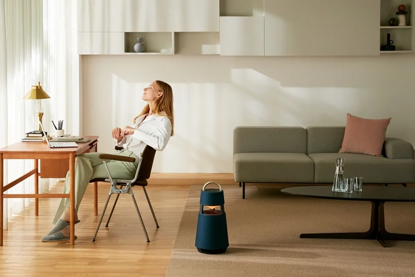 모델이 의자에 앉아 LG 엑스붐 360(모델명: RP4)로 음악을 감상하고 있다.