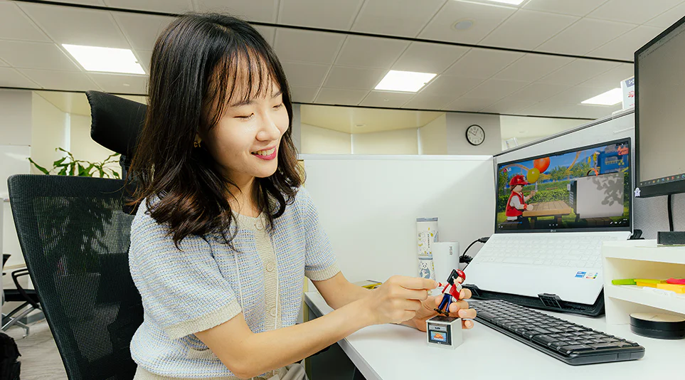 LG전자 플레이모빌을 기획한 이지원 선임이 사무실 책상에 앉아 플레이모빌 피규어 헨리를 들고 설명하고 있다