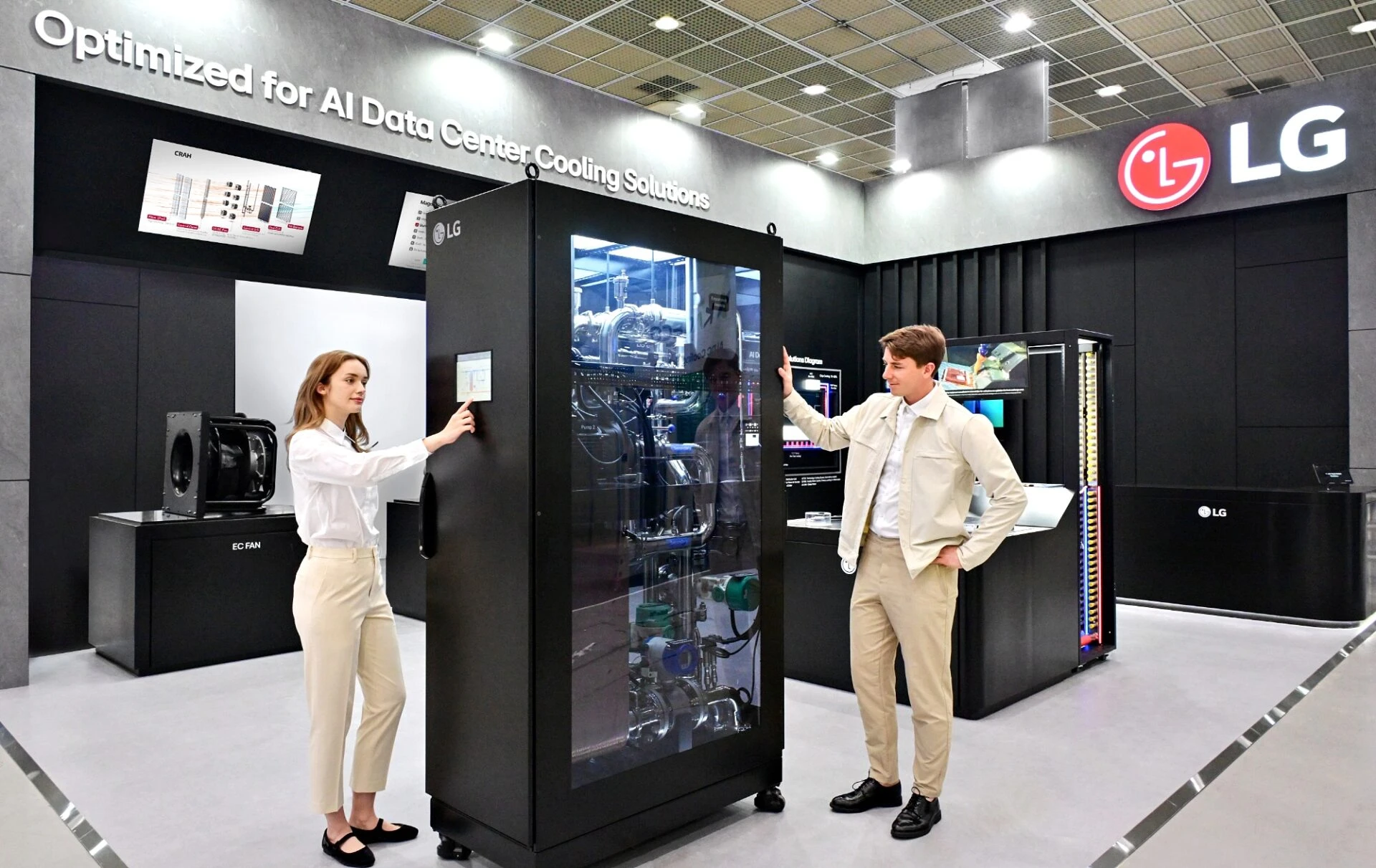 지난달 미국 워싱턴 D.C에서 열린 ‘데이터센터월드(Data Center World) 2025’에서 모델들이 AI 데이터센터 액체 냉각 솔루션인 CDU(Coolant Distribution Unit; 냉각수 분배 장치)를 소개하고 있다.
기기 앞면은 투명 커버로 내부 구조가 보이며, 한 여성이 측면 터치스크린을 조작 중이고 남성은 기기 옆에 손을 얹고 서 있다.
배경에는 “Optimized for AI Data Center Cooling Solutions”라는 문구가 벽면에 적혀 있고, LG 로고가 상단에 크게 배치되어 있다.
전시장 바닥과 벽은 모던한 회색 톤이며, 주변에는 다른 부품 전시대와 제품 안내 패널이 배치되어 있다.