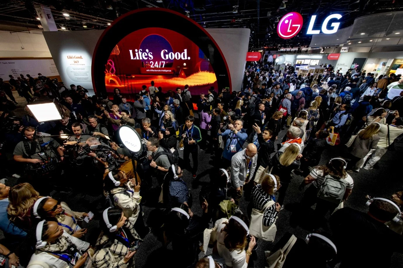 전시회 현장에서 LG 부스를 찾은 관람객들로 붐비는 모습. 중앙 대형 디스플레이에 'Life's Good 24/7' 문구가 선명히 보이며, 곳곳에서 사람들이 사진을 찍거나 설명을 듣고 있다. 상단에는 LG 로고가 설치돼 있다.