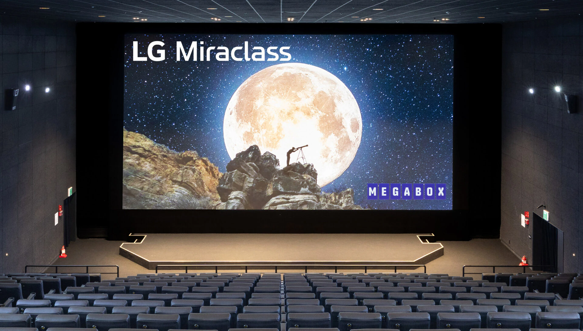 LG Miraclass 시네마 스크린이 설치된 메가박스 상영관 내부 전경. 대형 스크린에는 달과 밤하늘을 배경으로 한 이미지가 표시되어 있다.