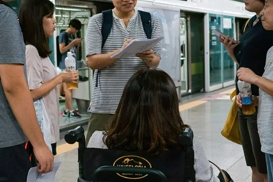 지하철역 승강장에서 휠체어 사용자를 포함한 여러 사람이 둘러 모여 대화를 나누고 있다. ⓒ무의 공식 홈페이지