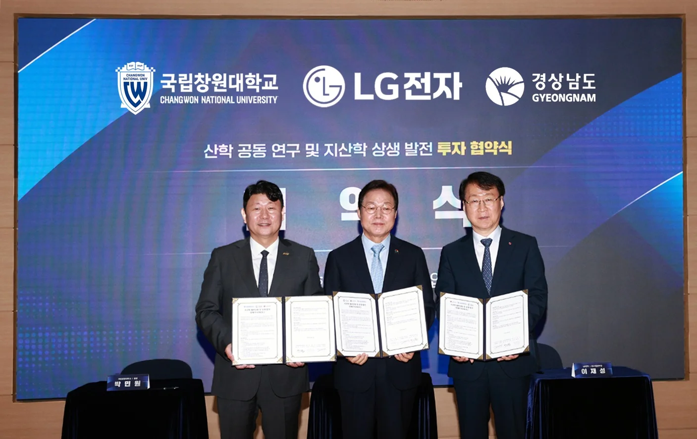 LG전자가 약 500억 원을 투자해 국립창원대 내 연면적 4천평 규모의 차세대 HVAC(냉난방공조) R&D 거점인 ‘LG전자 HVAC 연구센터’를 설립한다. 지역 내 우수 인재를 발굴하고 육성하기 위한 업무협약도 체결했다. 왼쪽부터 국립창원대학교 박민원 총장, 박완수 경상남도지사, LG전자 ES사업본부장 이재성 부사장. 뒤 배경 스크린에는 국립창원대학교, LG전자, 경상남도 로고와 함께 "산학 공동 연구 및 지산학 상생 발전 투자 협약식"이라는 문구가 표시되어 있다.